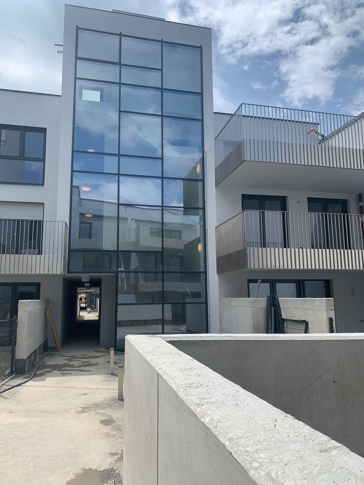 Verglaste Stiegenhausfassade eines Mehrfamilienhauses mit Kunststoff-Alu-Fenstern